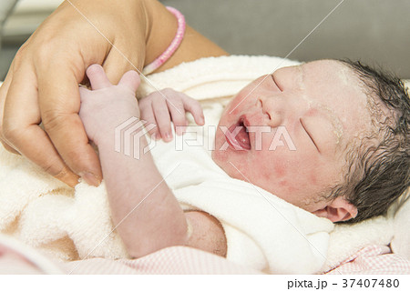 お母さんの指を掴む生まれたての赤ちゃんの写真素材