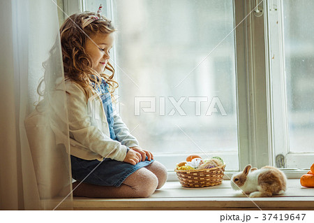 Beautiful happy child girl is sitting on window 37419647