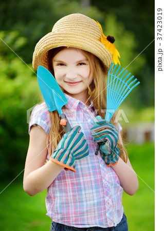 Adorable little girl wearing straw hat and childrens garden gloves holding garden tools Adorable little girl wearing straw hat and childrens garden gloves holding garden tools 37423019