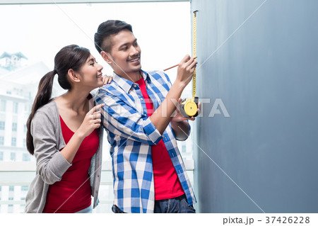 Young indonesian couple measuring walls in new 37426228