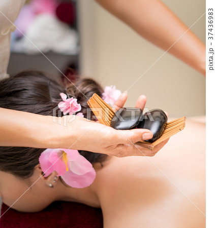 Spa therapist putting hot stone on a woman back Spa therapist putting hot stone on a woman back 37436983