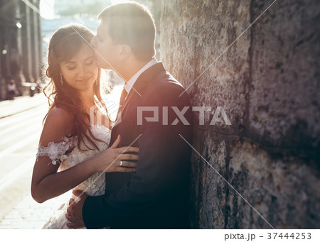 Handsome groom is kissing his charming bride in 37444253