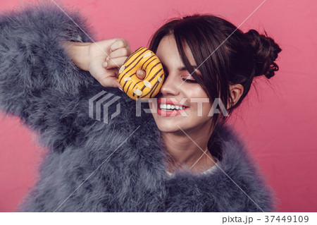 Beautiful girl in a fur coat with donuts in hands Beautiful girl in a fur coat with donuts in hands 37449109