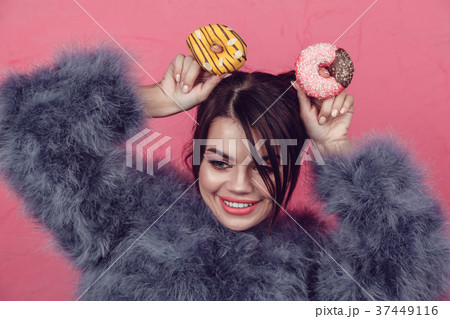 Beautiful girl in a fur coat with donuts in hands 37449116