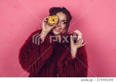 Girl in a bright fur coat with donuts in hands Girl in a bright fur coat with donuts in hands 37449209