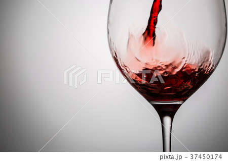 Pouring red wine into transparent glass 37450174