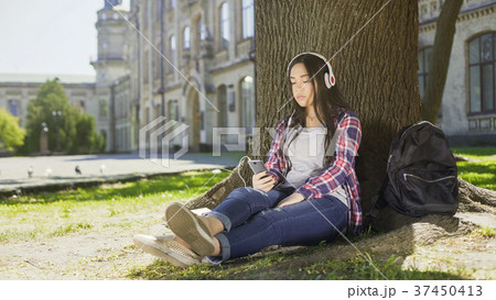 Multinational girl sitting under tree in 37450413