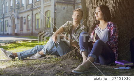 Multiracial male and female students sitting under Multiracial male and female students sitting under 37451030