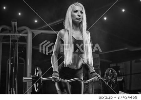 Young beautiful girl athlete bodybuilder at the gym doing exerci 37454469