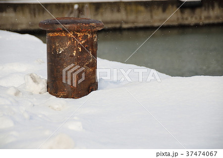 積雪のある岸壁に立つ係船柱。 37474067
