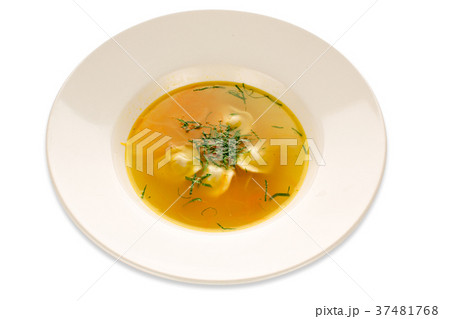 Cooked soup with greens in a white dish 37481768