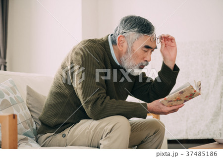 眼鏡を上げて本を読むシニア男性 37485186