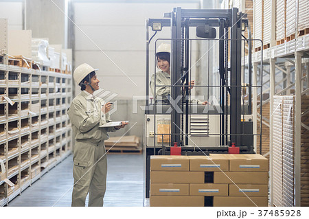 フォークリフトを操作する女性オペレーターと男性作業員の写真素材