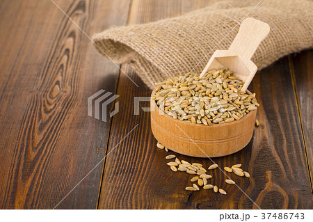 raw rye in a Cup on a wooden table and burlap. 37486743