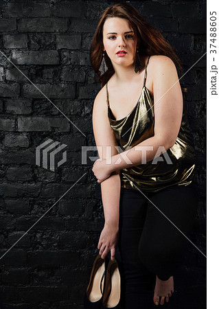 plus size model in a gold blouse and black jeans 37488605