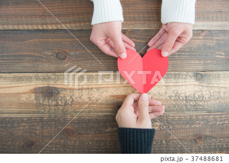 赤いハートを持っている手 木目のテーブル 37488681
