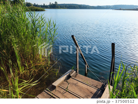 Summer lake calm beach with wood steeps to water 37500512