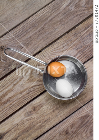 Two eggs in saucepan on wooden table Two eggs in saucepan on wooden table 37501472