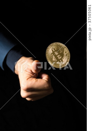 ビットコインをコイントスする右手の写真素材