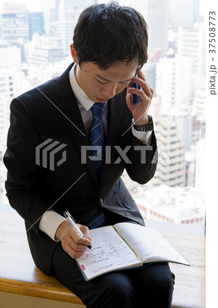 電話を受けながらスケジュール帳にメモする就活生のイメージ 37508773