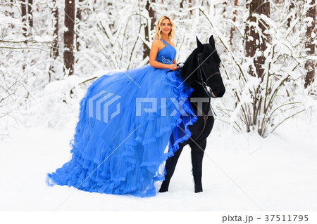 Young woman in long dress riding a horse in winter 37511795