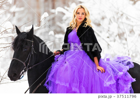 Young woman in long dress riding a horse in winter 37511796