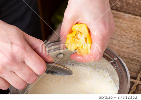 Squeezing lemon with metal spoon. Squeezing lemon with metal spoon. 37512352