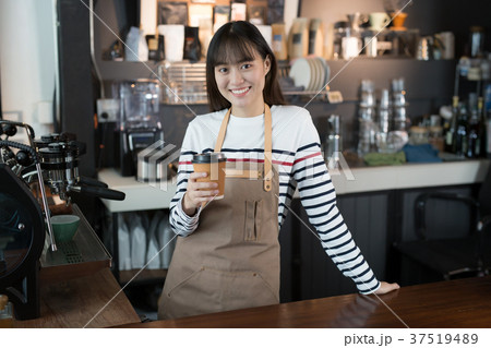 Asian woman barista standing with a coffee cup Asian woman barista standing with a coffee cup 37519489
