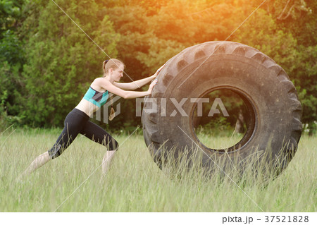 Girl in sportswear is pushing tire. Street workout Girl in sportswear is pushing tire. Street workout 37521828