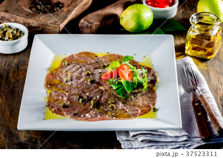 Beef carpaccio on white plate, wooden background 37523311