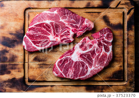 Raw marbled beef steaks on wooden cutting board Raw marbled beef steaks on wooden cutting board 37523370
