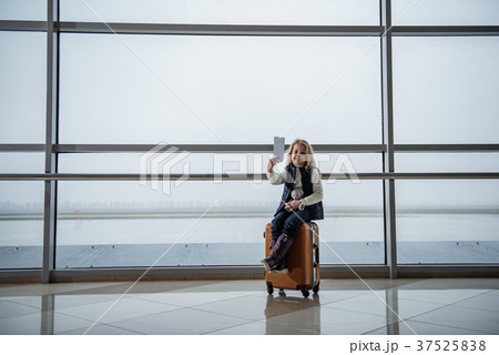 Smiling girl resting on big suitcase Smiling girl resting on big suitcase 37525838