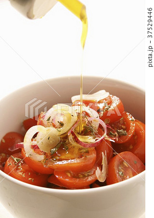 Drizzling olive oil over a tomato salad 37529446
