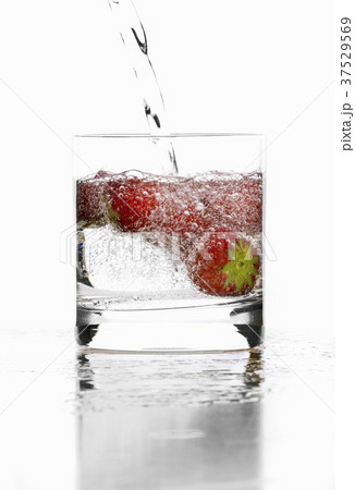 Mineral water in a glass, garnished with strawberries 37529569