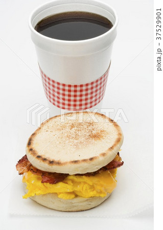 Scrambled egg and bacon in English muffin, cup of coffee 37529901