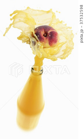 Peach juice splashing out of bottle 37532598