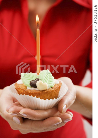 Woman holding cupcake with marzipan leaves and candle 37533126