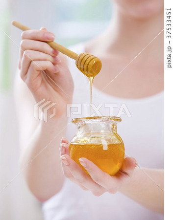 Young woman holding jar of honey and honey dipper Young woman holding jar of honey and honey dipper 37533451
