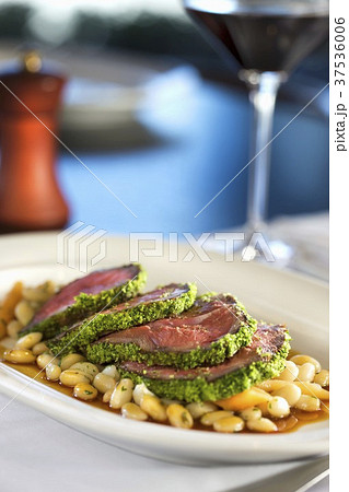 Sliced Herb Crusted Lamb Served Over White Beans 37536006
