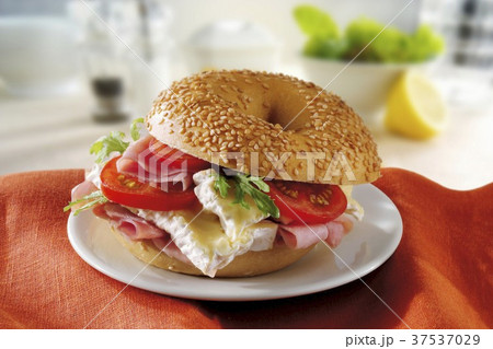 A sesame seed bagel with brie, ham and tomatoes 37537029