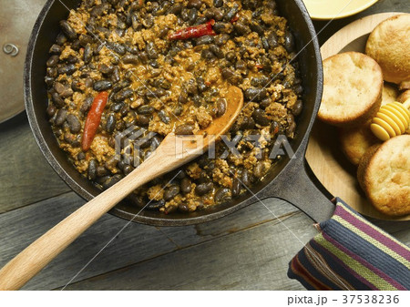 Chili in a Cast Iron Pot with a Wooden Spoon; Corn Muffins 37538236