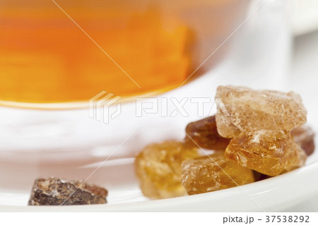 Rock sugar in front of a glass of tea (close-up) 37538292