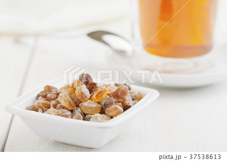 Rock sugar in front of a glass of tea Rock sugar in front of a glass of tea 37538613