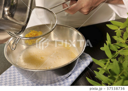 Straining reduced orange syrup through a sieve 37538736
