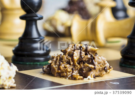 Nut brittle drizzled with chocolate on a chessboard 37539090