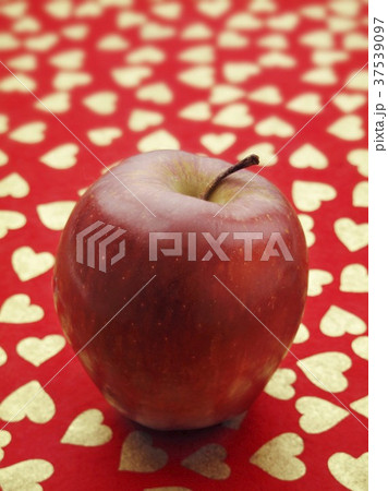 A red apple on a red surface patterned with hearts 37539097
