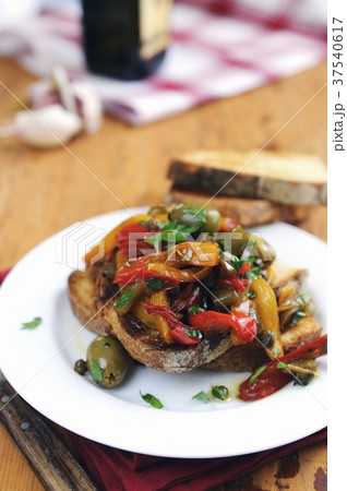 Bruschetta topped with red and yellow peppers, olives and capers 37540617