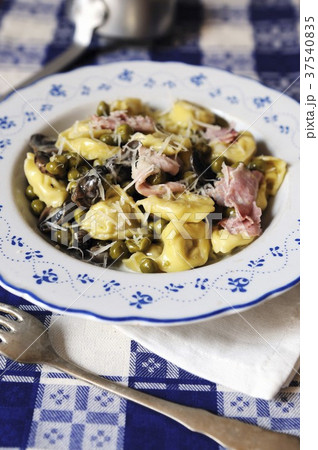 Cheese filled tortelli with a creamy ham, mushroom and pea sauce topped with parmesan cheese Cheese filled tortelli with a creamy ham, mushroom and pea sauce topped with parmesan cheese 37540835