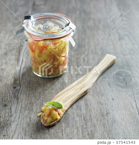 Jar of Homemade Mango Salsa; Some on a Wooden Spoon 37541543