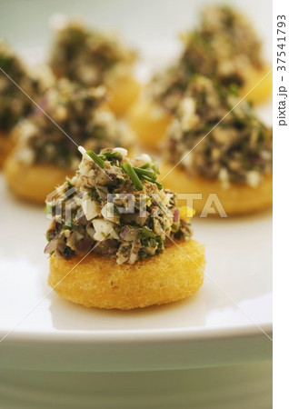 Round slices of toast topped with aardine and parsley salad 37541793